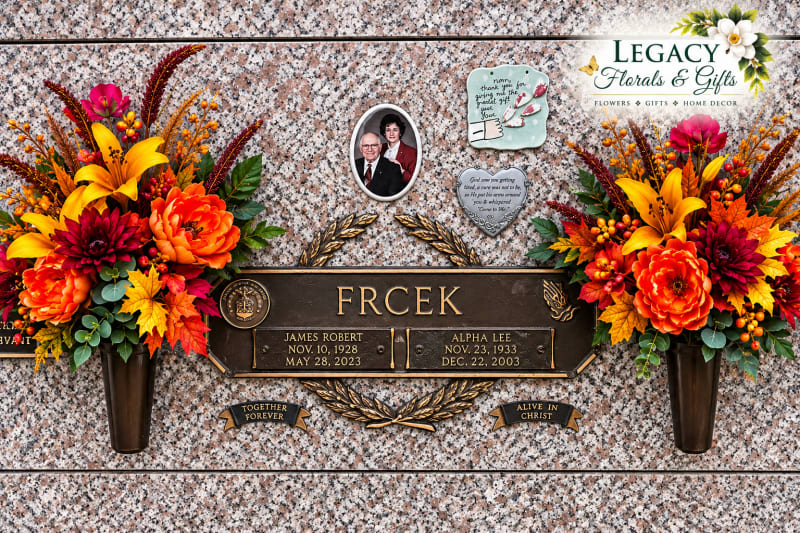Coordinating orange, burgundy, and gold memorial floral arrangements displayed in cemetery mausoleum wall vases by Legacy Florals & Gifts.