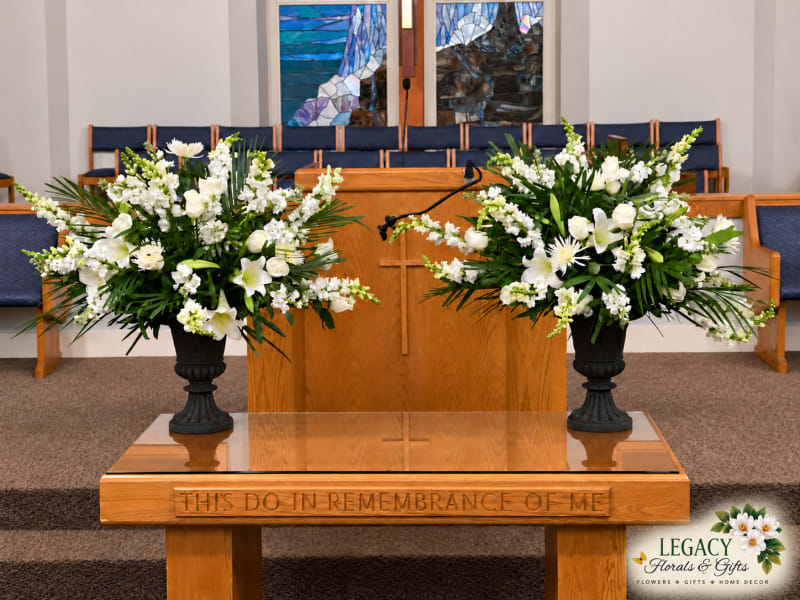 Elegant white blooms and lush greenery frame the altar in coordinated arrangements by Legacy Florals & Gifts in Lawrenceville, Georgia. A graceful floral design for worship services and special church occasions.