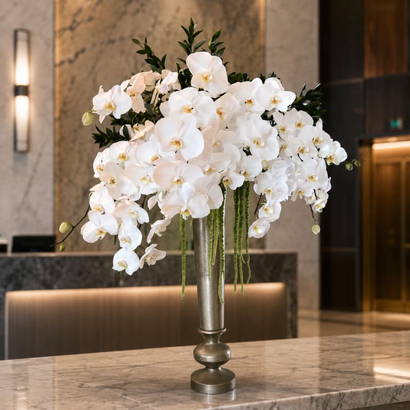 white phalaenopsis hanging orchids in a gold tall vase.
